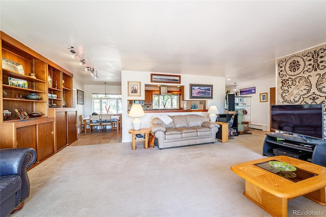 carpeted living room featuring a baseboard radiator and a notable chandelier