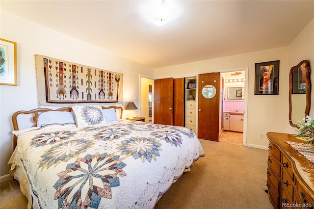 bedroom with ensuite bath and light carpet