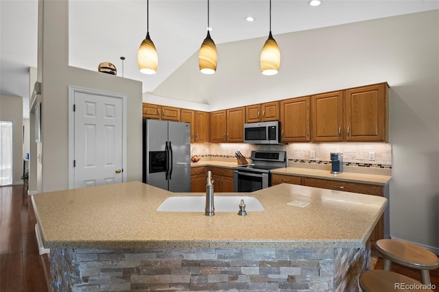 1376 Banner Cir, Erie, CO 80516 - kitchen with stainless steel appliances, a breakfast bar, decorative backsplash, brown cabinetry, and high vaulted ceiling