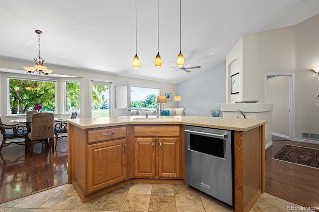 1376 Banner Cir, Erie, CO 80516 - kitchen featuring stainless steel dishwasher, light countertops, brown cabinets, hanging light fixtures, and vaulted ceiling