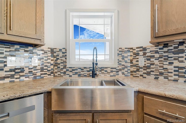 kitchen with tasteful backsplash, dishwasher, light stone countertops, and sink