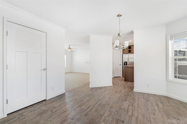 unfurnished living room with crown molding, wood-type flooring, and ceiling fan with notable chandelier