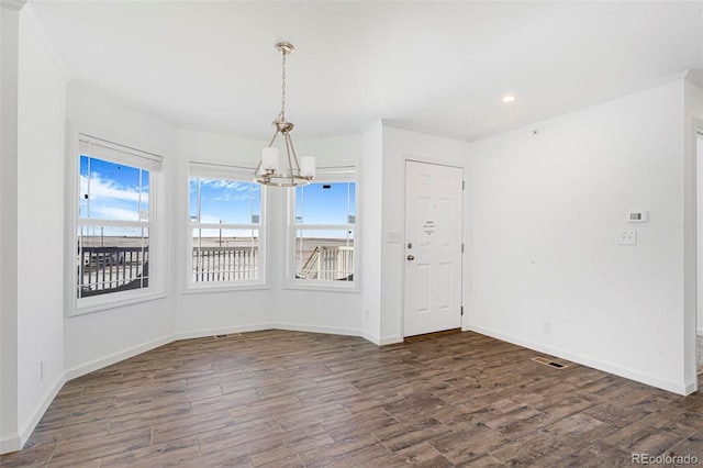 empty room with a chandelier and dark hardwood / wood-style flooring