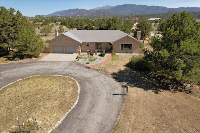 510 Crossman Ave, Buena Vista, CO 81211 - ranch-style house with a chimney, brick siding, asphalt driveway, a mountain view, and a garage