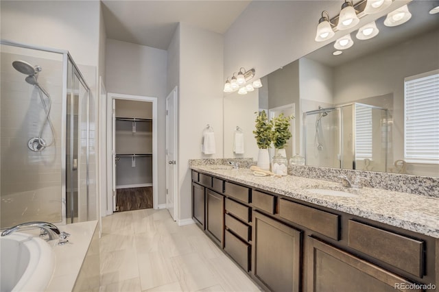 full bathroom with a stall shower, a walk in closet, a sink, and double vanity