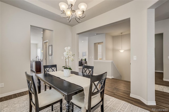 dining area featuring baseboards, wood finished floors, and a notable chandelier