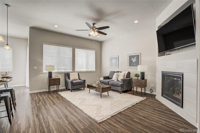 living room featuring a fireplace, recessed lighting, dark wood-type flooring, a ceiling fan, and baseboards