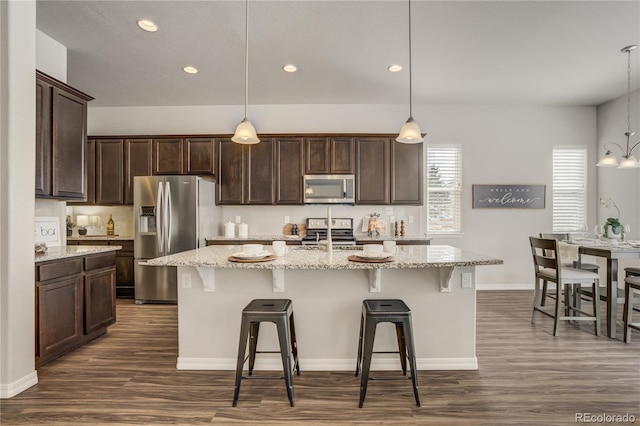 kitchen featuring stainless steel appliances, a breakfast bar, dark brown cabinets, and dark wood-style floors