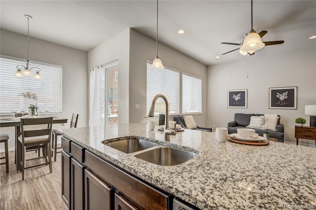 kitchen with open floor plan, decorative light fixtures, a sink, and dark brown cabinets