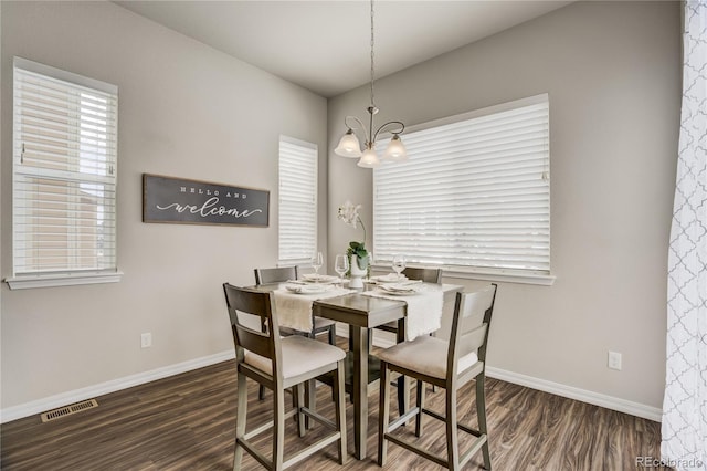 dining space with baseboards, wood finished floors, visible vents, and a notable chandelier