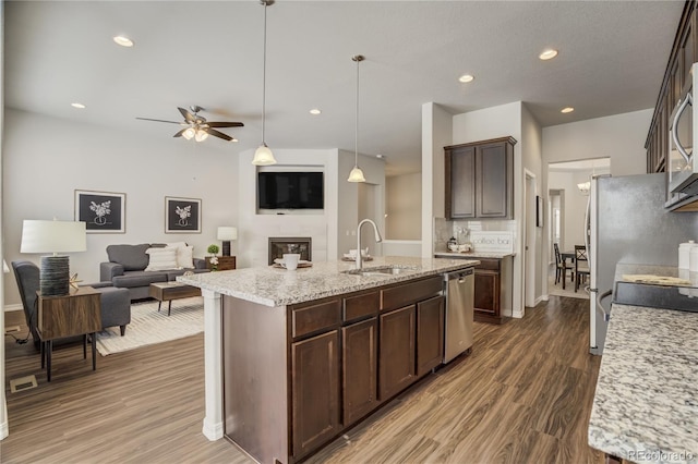 kitchen with stainless steel appliances, a sink, dark brown cabinetry, and wood finished floors