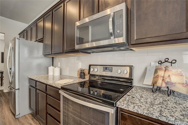 kitchen featuring appliances with stainless steel finishes, backsplash, light wood finished floors, and dark brown cabinets