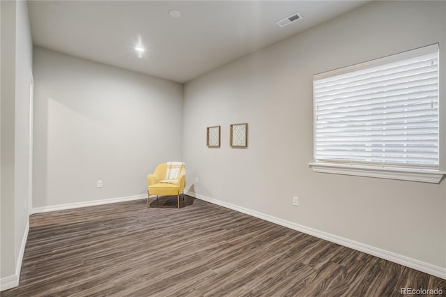 unfurnished room featuring dark wood-type flooring, visible vents, and baseboards