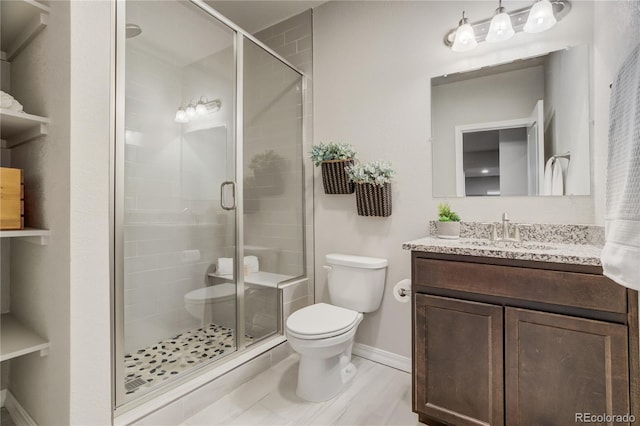 full bath with a stall shower, vanity, toilet, and baseboards