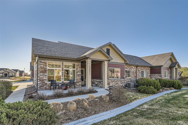12625 Madison Way, Thornton, CO 80241 - view of front of house featuring central air condition unit, roof with shingles, and stone siding