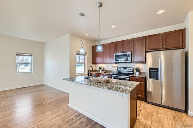 12625 Madison Way, Thornton, CO 80241 - kitchen with light wood-style floors, dark stone counters, an island with sink, hanging light fixtures, and stainless steel appliances