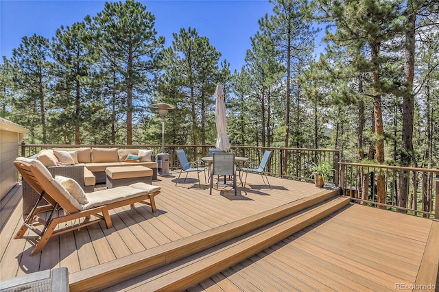 7753 Red Fox Dr, Evergreen, CO 80439 - deck featuring an outdoor living space, outdoor dining area, and view of wooded area