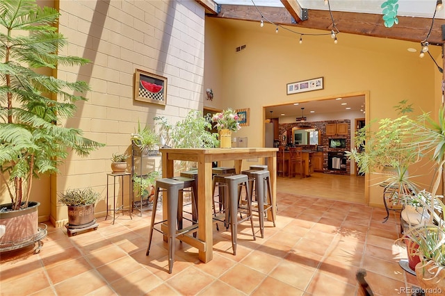 7753 Red Fox Dr, Evergreen, CO 80439 - bar featuring high vaulted ceiling, black microwave, light tile patterned floors, and beam ceiling