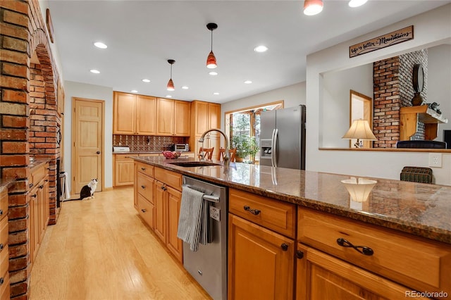 7753 Red Fox Dr, Evergreen, CO 80439 - kitchen featuring appliances with stainless steel finishes, a sink, light wood-type flooring, dark stone countertops, and tasteful backsplash