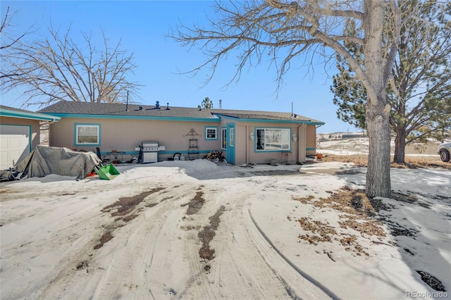 snow covered back of property featuring a garage