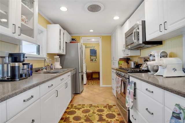 kitchen with sink, white cabinetry, light tile patterned floors, ornamental molding, and appliances with stainless steel finishes