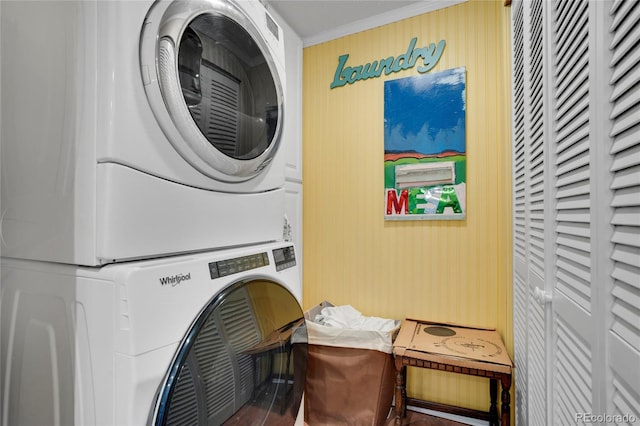 laundry area with ornamental molding and stacked washer / drying machine