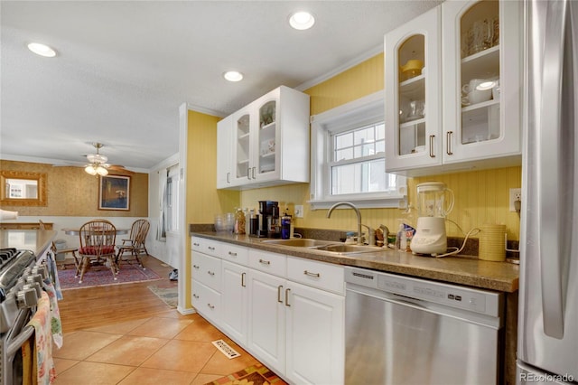 kitchen featuring sink, white cabinetry, crown molding, light tile patterned floors, and appliances with stainless steel finishes