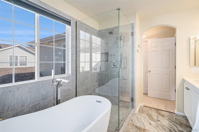 8300 Fairmount Dr Unit M103, Denver, CO 80247 - full bath featuring a shower stall, a soaking tub, vanity, marble finish floors, and baseboards