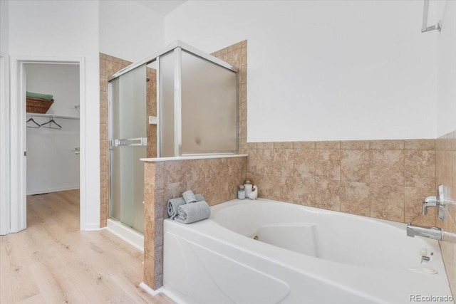 3862 E 127th Ln, Thornton, CO 80241 - bathroom featuring a stall shower, a bath, wood finished floors, and a walk in closet
