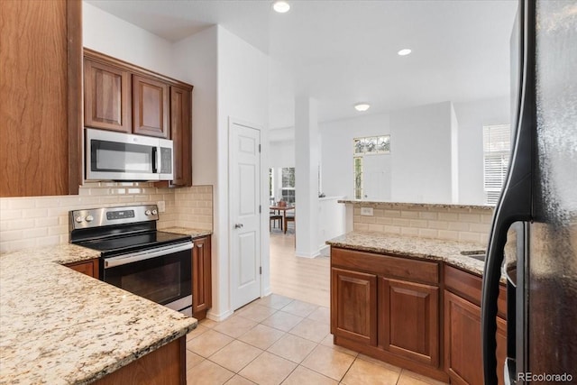 3862 E 127th Ln, Thornton, CO 80241 - kitchen featuring stainless steel appliances, light tile patterned floors, backsplash, light stone countertops, and brown cabinetry