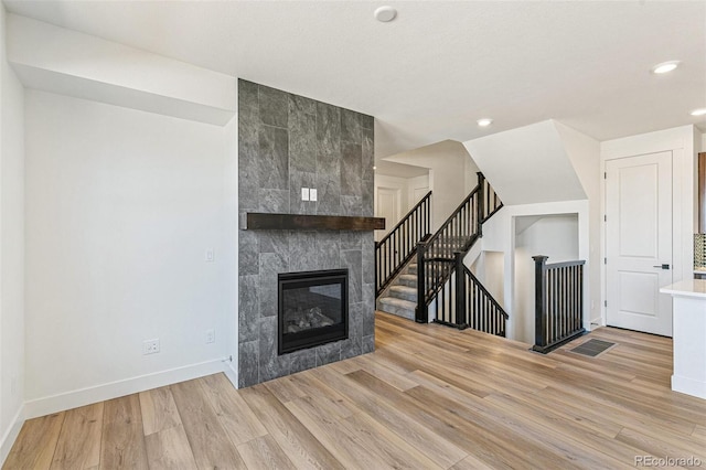 28564 E 6th Pl, Watkins, CO 80137 - unfurnished living room featuring a fireplace, light wood-style flooring, recessed lighting, and stairs