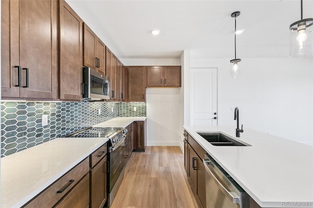28564 E 6th Pl, Watkins, CO 80137 - kitchen featuring stainless steel appliances, light wood-style floors, light countertops, backsplash, and decorative light fixtures