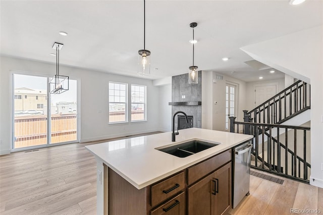 28564 E 6th Pl, Watkins, CO 80137 - kitchen with stainless steel dishwasher, light wood-style flooring, light countertops, a large fireplace, and an island with sink