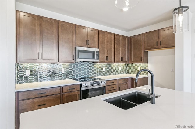 28564 E 6th Pl, Watkins, CO 80137 - kitchen featuring stainless steel appliances, light countertops, decorative backsplash, and pendant lighting