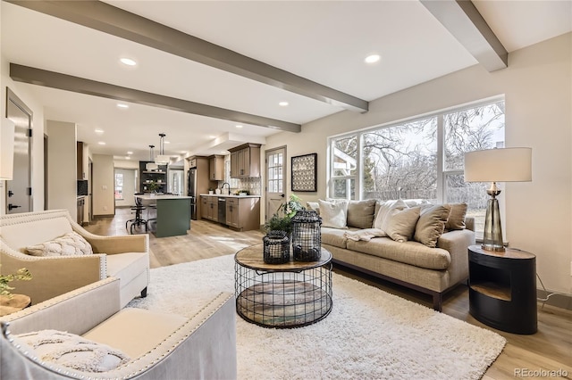 living room featuring sink, light hardwood / wood-style flooring, and beamed ceiling