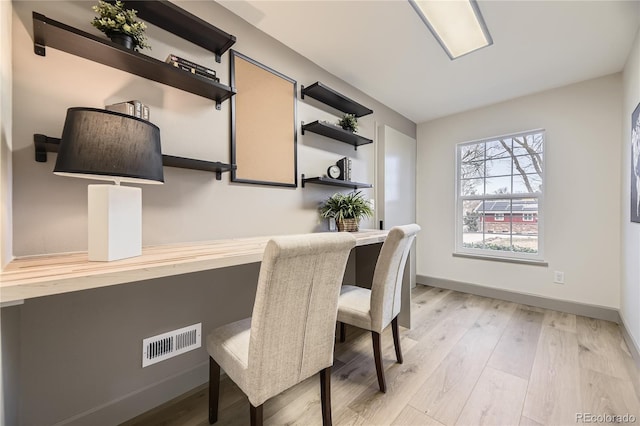 office space with built in desk and light wood-type flooring