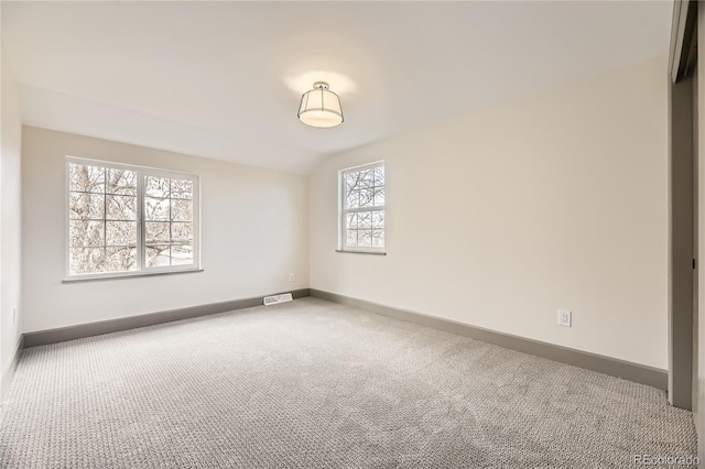 carpeted empty room featuring lofted ceiling