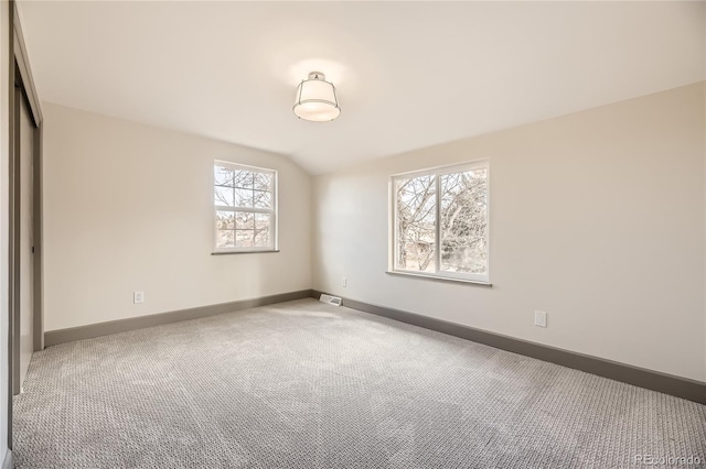 carpeted spare room with vaulted ceiling