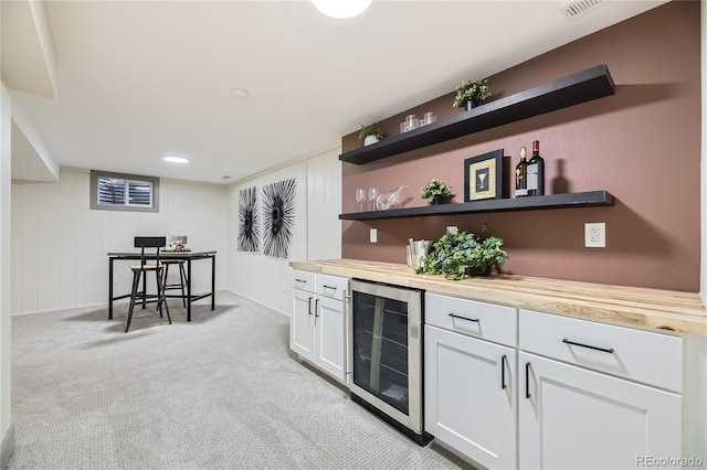 bar with wine cooler, wood counters, light colored carpet, and white cabinets