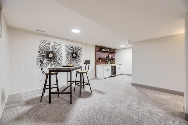 interior space featuring bar, light colored carpet, and beverage cooler