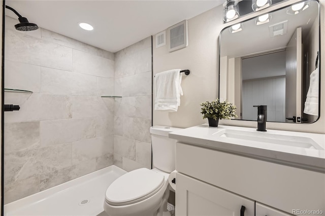 bathroom with vanity, toilet, and a tile shower