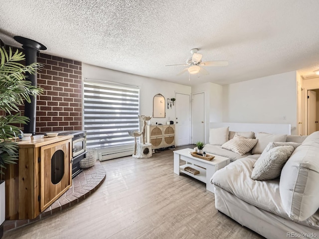 10895 Fairfax Way, Thornton, CO 80233 - living area with a wood stove, a textured ceiling, ceiling fan, light wood-style floors, and a baseboard heating unit