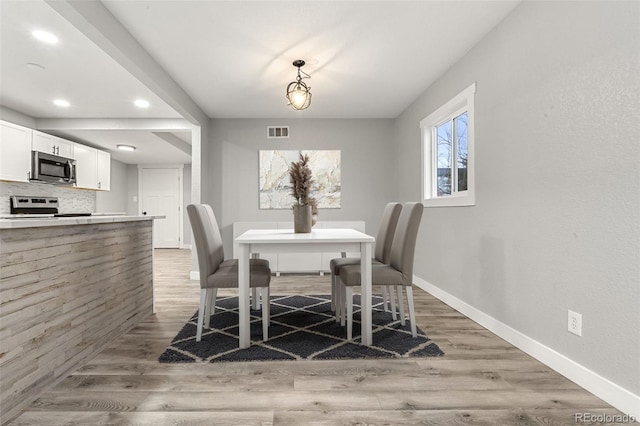 dining room with light wood-style floors, baseboards, visible vents, and recessed lighting