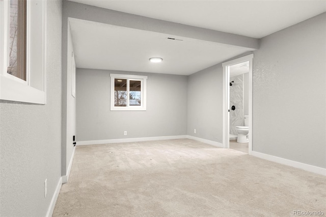 spare room featuring light colored carpet and baseboards