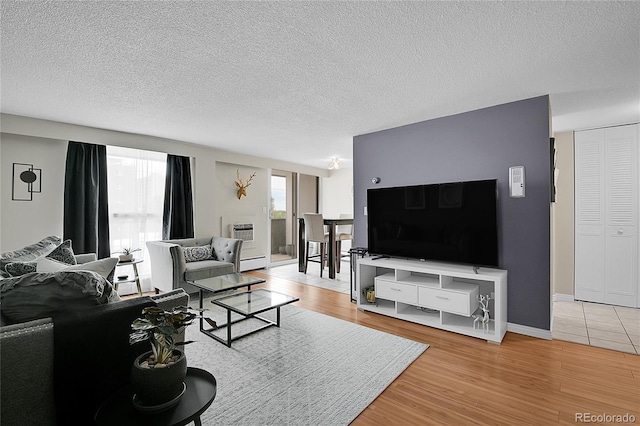 living room featuring a textured ceiling, baseboards, and wood finished floors