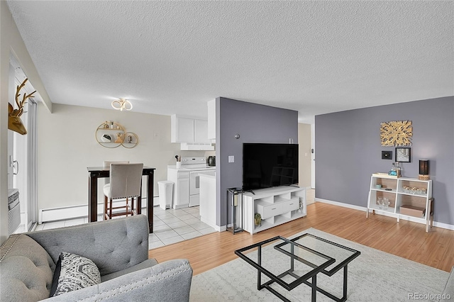 living room featuring a textured ceiling, baseboard heating, washing machine and dryer, and light hardwood / wood-style floors