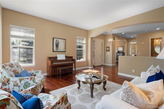 living room with arched walkways, wood finished floors, healthy amount of natural light, baseboards, and recessed lighting