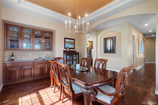 dining area featuring dark wood-style floors, arched walkways, baseboards, recessed lighting, and bar area