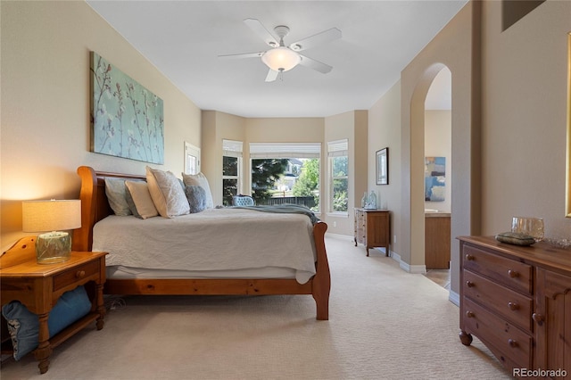 bedroom with light carpet, arched walkways, baseboards, and a ceiling fan