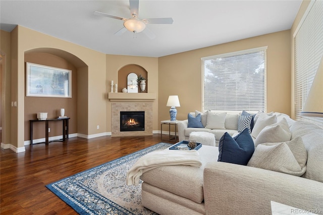 living room with wood finished floors, a ceiling fan, a fireplace, and baseboards